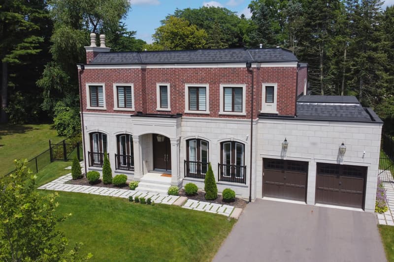 The house on Grayson Green Court from above: red brick over a cut-stone ground floor, arched windows, a double garage and a fenced lawn
